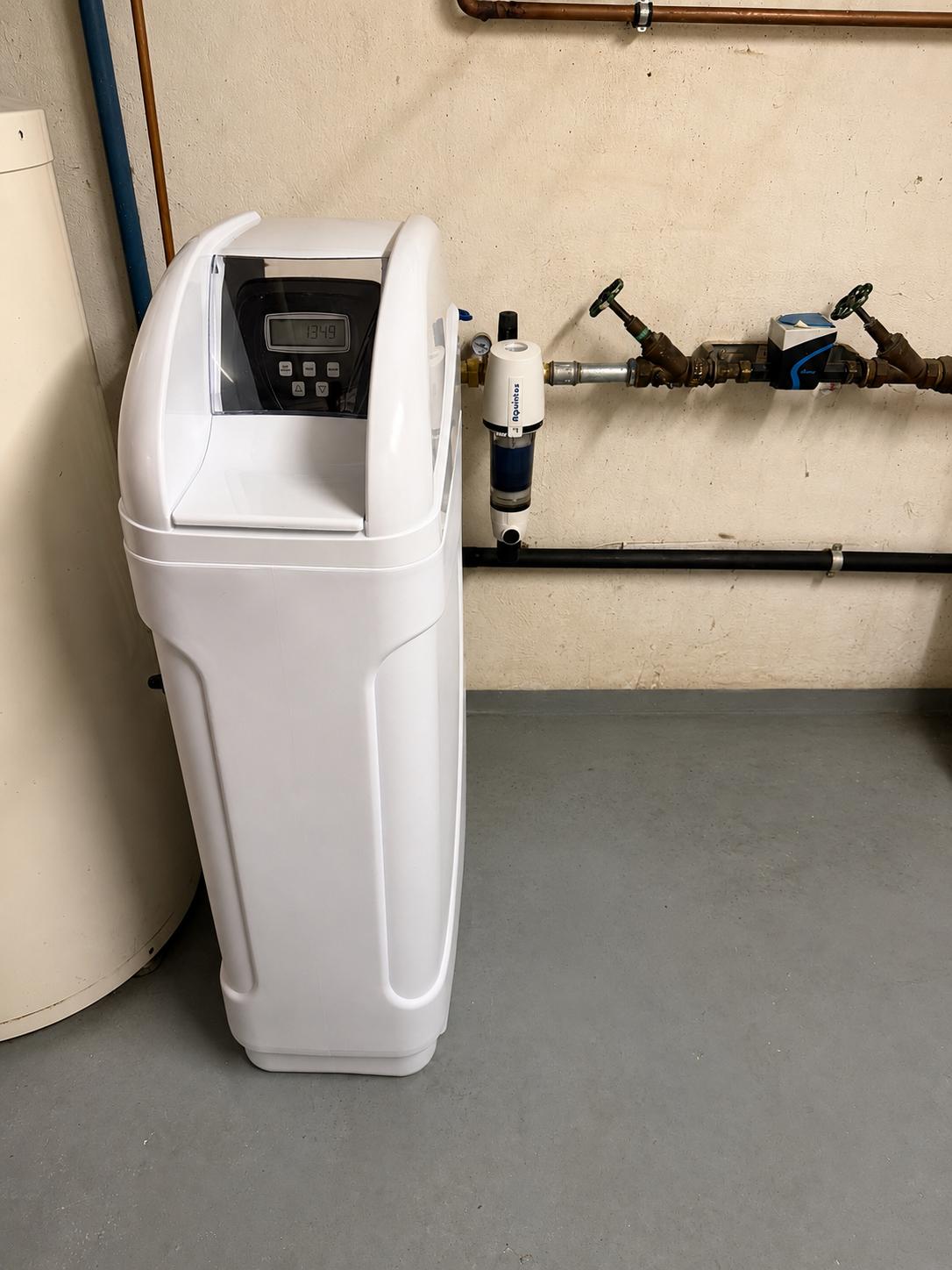 Enthärtungsanlage neben Wasserzähler und Filter im Keller